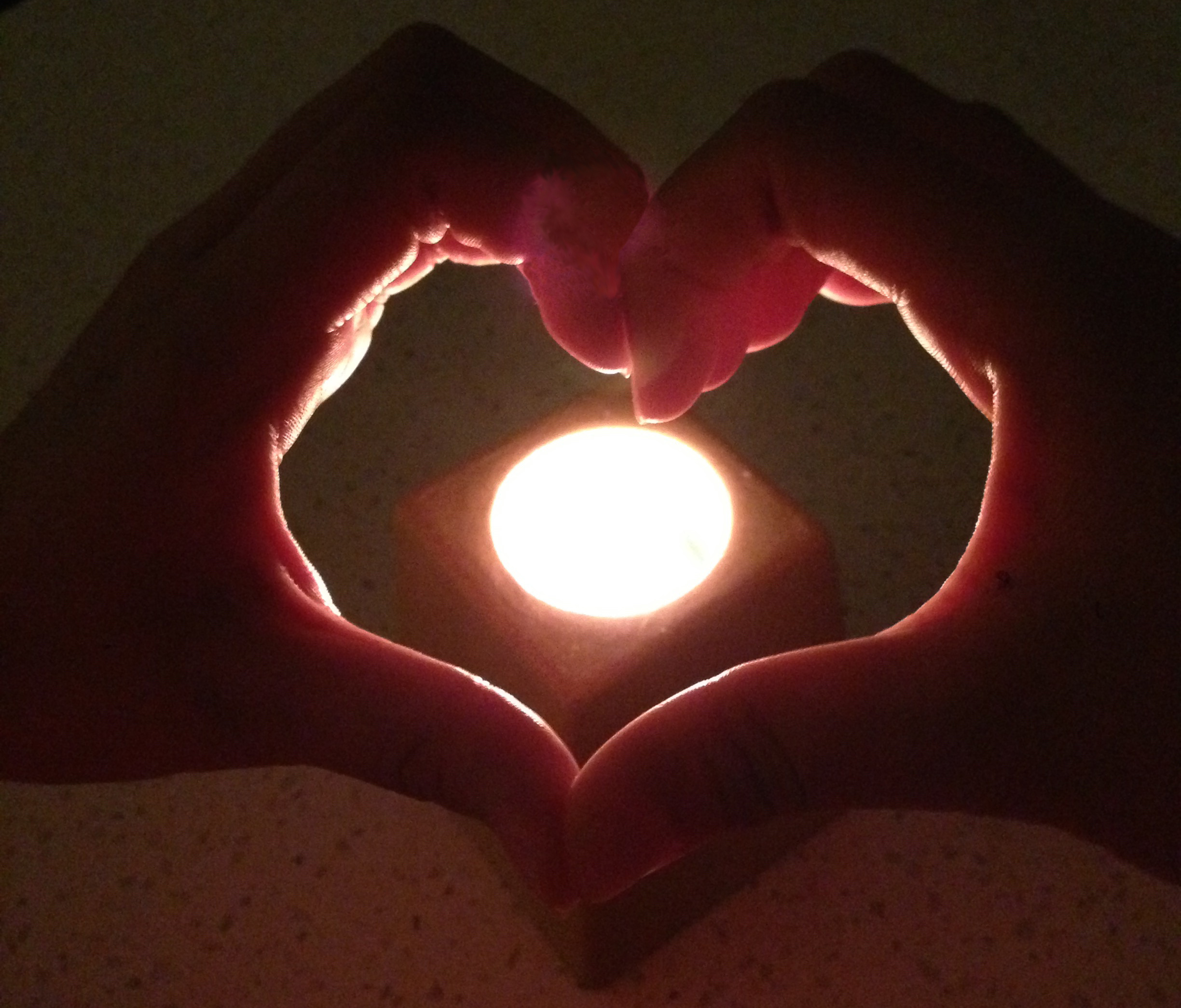 Candle with hands in shape of heart.